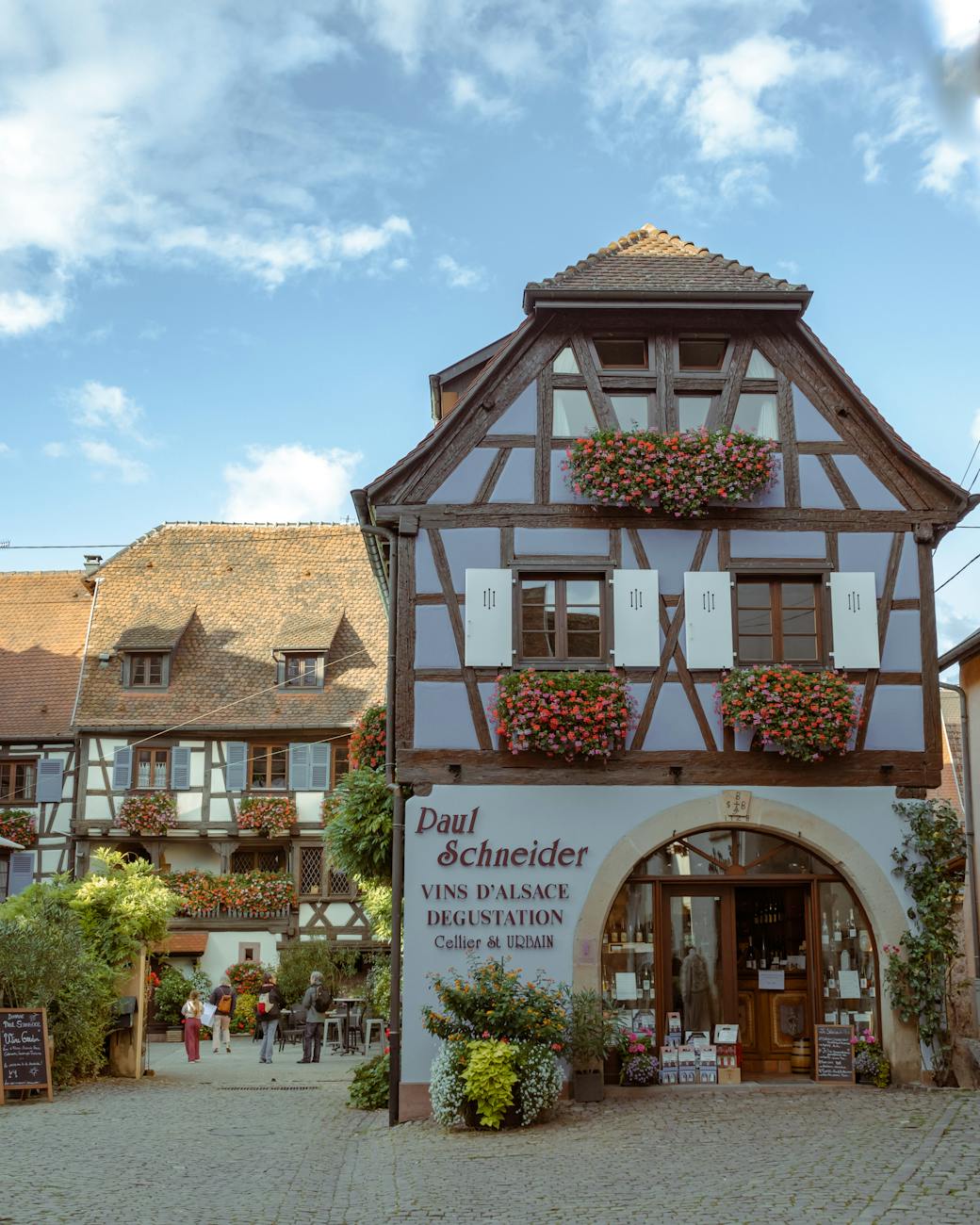 Maisons a colombages colorees avec geraniums en fleurs a Eguisheim